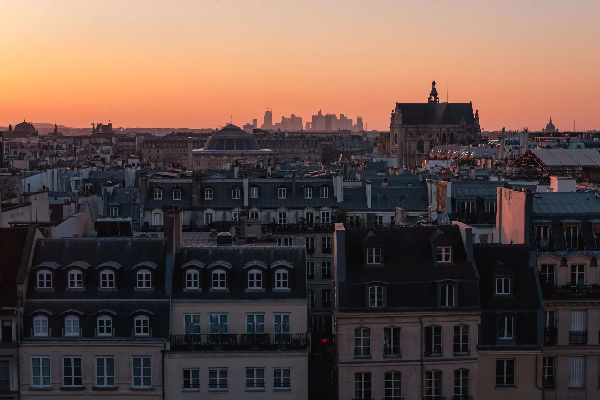 Les toits de Paris sous un ciel orangé au coucher du soleil
